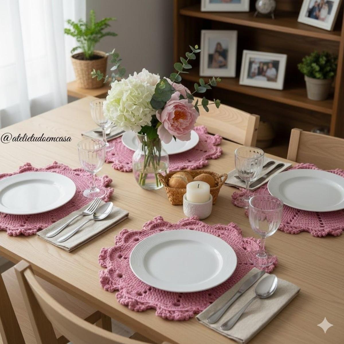 Mesa posta com sousplats artesanais em tom rosé, louças brancas e arranjo floral